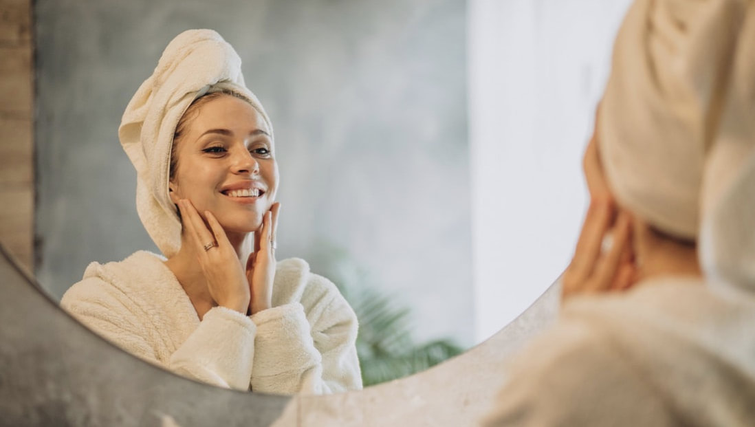 Woman smiling and looking in mirror after a spa facial